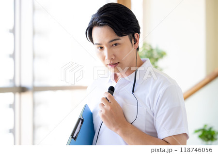 ワイヤレスマイクをつけて働く男性介護士 118746056