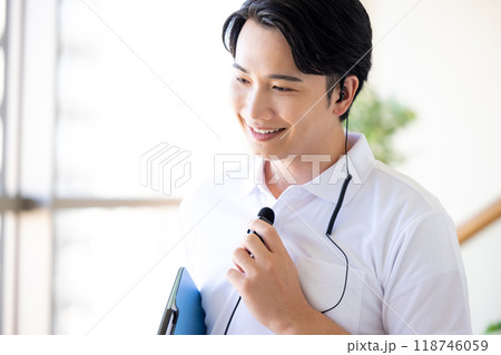 ワイヤレスマイクをつけて働く男性介護士 118746059