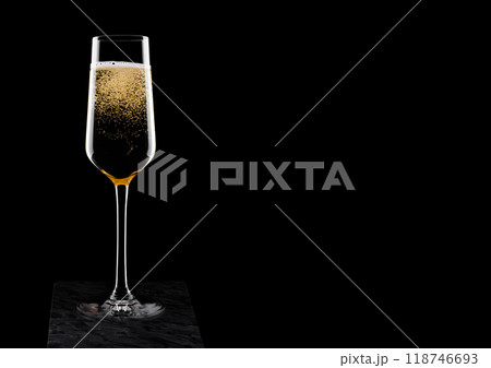 Elegant glass of yellow champagne with bubbles on black marble board on black background. Space for text Elegant glass of yellow champagne with bubbles on black marble board on black background. Space for text 118746693