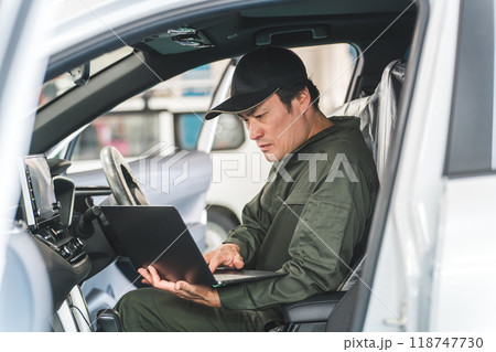 自動車の車内でノートパソコンを使う自動車整備士の男性 自動車の車内でノートパソコンを使う自動車整備士の男性 118747730