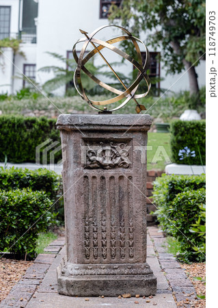 Brass or bronze large scale armillary sundial sphere with raised roman numerals and arrow directional on plinth, stone pedestal with pattern. Brass or bronze large scale armillary sundial sphere with raised roman numerals and arrow directional on plinth, stone pedestal with pattern. 118749703