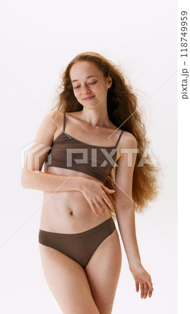Portrait of beautiful young woman with slim body, long hair, posing in cotton underwear isolated on white studio background. Wellness Portrait of beautiful young woman with slim body, long hair, posing in cotton underwear isolated on white studio background. Wellness 118749959