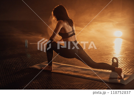An Elegant Woman Engaged in a Yoga Session Under Dramatic Lighting A Source of Inspiration for Fitness and Wellness Enthusiasts, Showcasing Balance, Calmness, and Concentration in Movement 118752837
