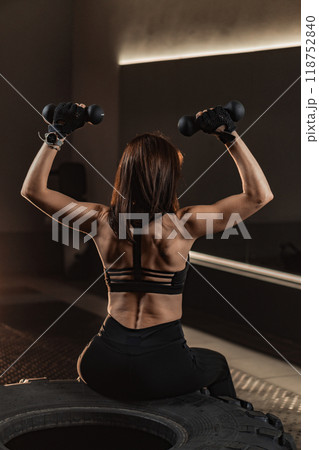 In a modern gym, a strong woman lifts dumbbells, showcasing her commitment to health and fitness, inspiring others to start their wellness journeys and fostering a community focused on strength In a modern gym, a strong woman lifts dumbbells, showcasing her commitment to health and fitness, inspiring others to start their wellness journeys and fostering a community focused on strength 118752840