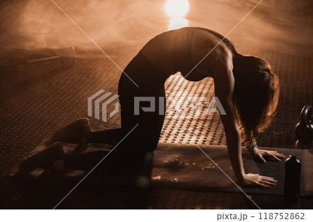 A woman in a vibrant fitness scene shows intense focus during her workout. Her determination and balance are crucial for optimal health, highlighting mindfulness and motivation in exercise 118752862