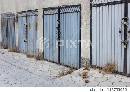 Entrances to parking spaces for cars in the courtyard of an apartment building. Lots of metal garage doors. Garage cooperative. 118753956