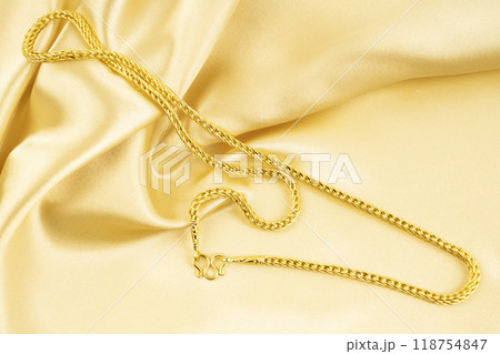 Gold Necklace on gold color silk background. Gold Necklace on gold color silk background. 118754847