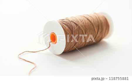 A close-up of a spool of brown thread placed on a white background, representing crafting, sewing, or DIY projects. The simplicity highlights the importance of everyday materials. 118755881