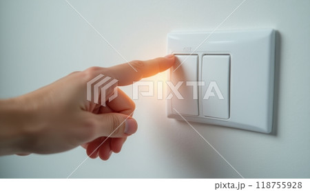 A close-up of a hand turning off a white light switch on a clean wall, representing energy-saving, control, and responsibility. The image conveys simplicity and environmental awareness. 118755928