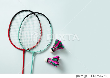 White feather badminton shuttlecocks and two badminton rackets on light blue background. View from above. Copy space. Concept racket sport. Leisure games. 118756730