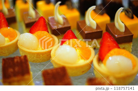 Beautiful multicolored decorated baked sweet tasty party cakes or catering cakes for party, bar dessert selection with cake, pie and pastries catering banquet, coffee break buffet at a conference Beautiful multicolored decorated baked sweet tasty party cakes or catering cakes for party, bar dessert selection with cake, pie and pastries catering banquet, coffee break buffet at a conference 118757141