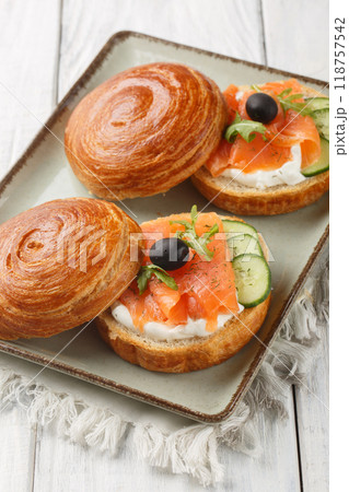 Crispy puff pastry sandwich with smoked salmon, cream cheese, cucumber and olives close-up on a plate. Vertical Crispy puff pastry sandwich with smoked salmon, cream cheese, cucumber and olives close-up on a plate. Vertical 118757542