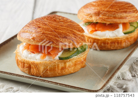 Puff pastry bun sandwich with smoked salmon, cream cheese, cucumber and olives close-up on plate. Horizontal Puff pastry bun sandwich with smoked salmon, cream cheese, cucumber and olives close-up on plate. Horizontal 118757543