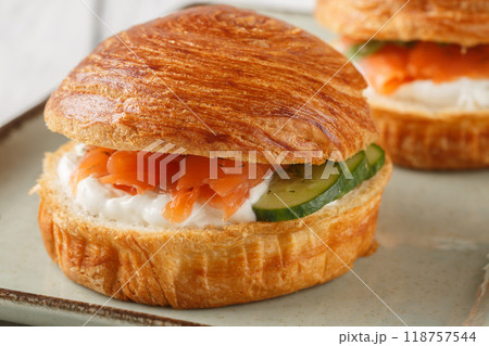 Delicious brioche sandwich with smoked salmon, cream cheese, cucumber and olives close-up on plate. Horizontal Delicious brioche sandwich with smoked salmon, cream cheese, cucumber and olives close-up on plate. Horizontal 118757544