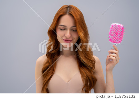 Ginger young woman holding a pink hairbrush in hands 118758132