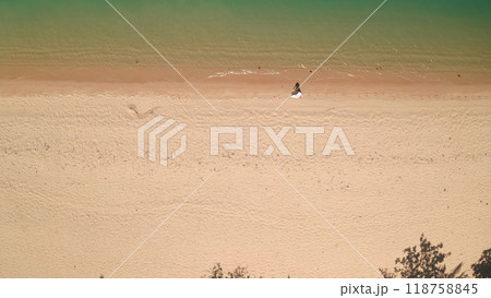 Aerial top down sand beach texture water waves. Woman walking coastline, clear, ideal shore, relax, enjoy outdoor lifestyle travel on summer holiday vacation. Drone view shot. Background 118758845