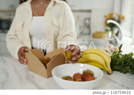Preparing Fresh Rambutan While Holding Open Box 118759618