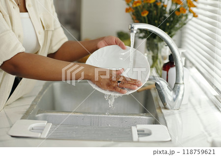 Washing Dishes Under Running Water in a Modern Kitchen 118759621