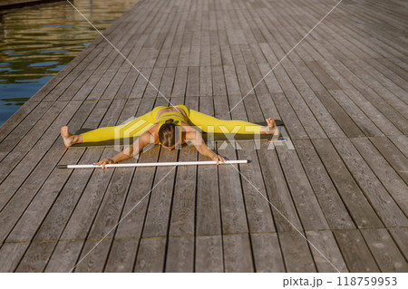 A graceful Flexible Stretching Pose on a Dock by calm Water, showcasing tranquility and balance A graceful Flexible Stretching Pose on a Dock by calm Water, showcasing tranquility and balance 118759953