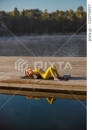 Engaging in a Serene Yoga Practice by the Water as the Sun Rises in the Morning Light Engaging in a Serene Yoga Practice by the Water as the Sun Rises in the Morning Light 118759957
