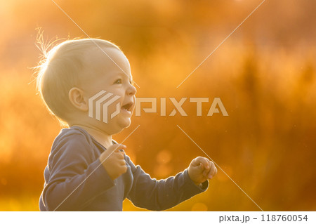 Baby boy laughing and having fun outside at golden hour 118760054