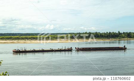 A large river vessel pulls two barges loaded with timber down the river 118760602