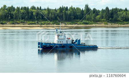 A large river vessel pulls two barges loaded with timber down the river A large river vessel pulls two barges loaded with timber down the river 118760604