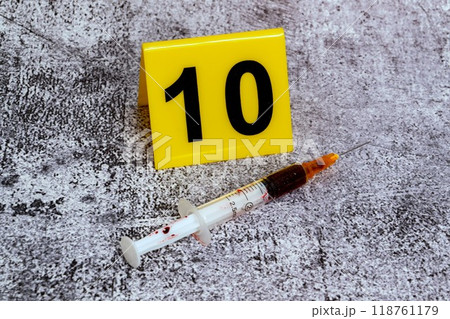 drugs at the crime scene. yellow markers with forensic numbers. syringe with a dose 118761179