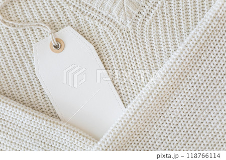 White blank label on a background of white knitted clothing. White blank label on a background of white knitted clothing. 118766114