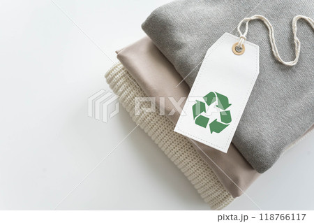 A neat stack of knitted clothing with a recycle label. White background. 118766117