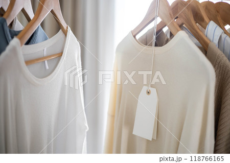 Knitted clothes in neutral shades hang on hangers. Blank label. 118766165