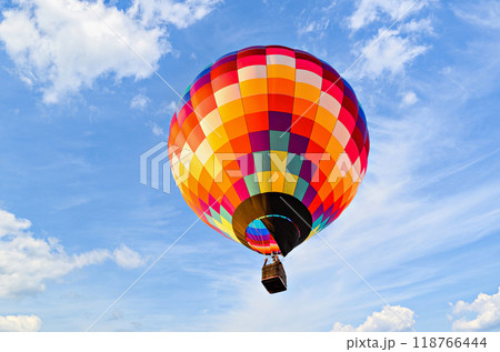 Colorful hot air balloon flying over blue sky with white clouds Colorful hot air balloon flying over blue sky with white clouds 118766444