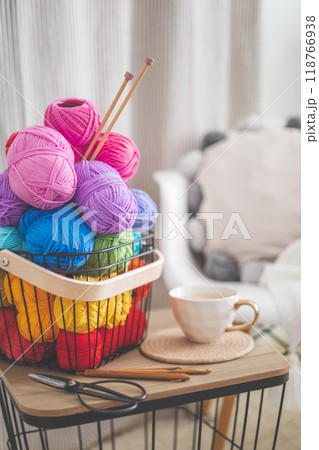 Cozy homely atmosphere. Female hobby knitting. Yarn pastel multicolor in a basket.  118766938