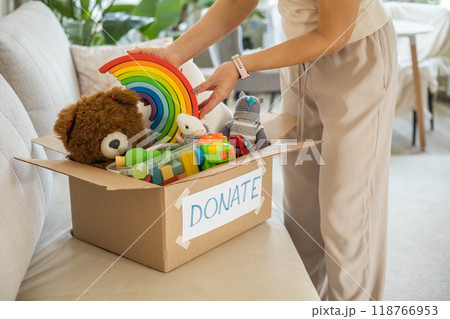 A woman puts toys in a cardboard box for charity. Donation concept. 118766953