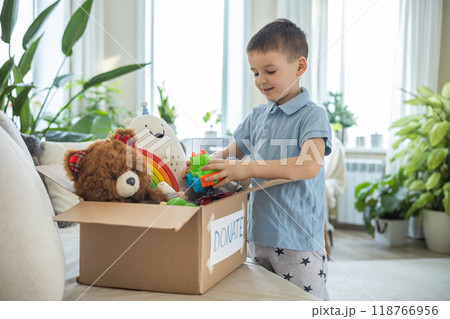 Boy child puts toys in a cardboard box for charity. Donation concept. Boy child puts toys in a cardboard box for charity. Donation concept. 118766956