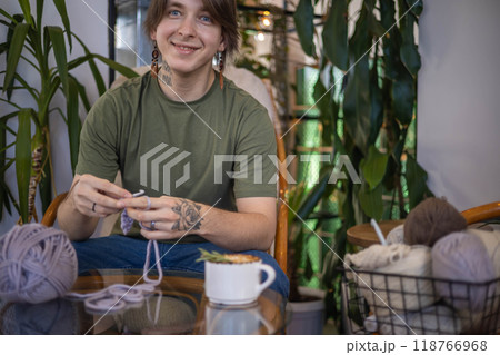 Hipster creative man crochet handmade use knitting supplies hook and wool yarn on couch at home Hipster creative man crochet handmade use knitting supplies hook and wool yarn on couch at home 118766968