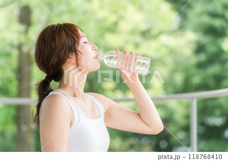 公園・森林の中でミネラルウォーターを飲む若いアジア人女性 公園・森林の中でミネラルウォーターを飲む若いアジア人女性 118768410