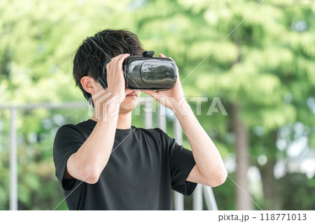 VRゴーグルをつけてバーチャルリアリティ・メタバースを体験する男性 VRゴーグルをつけてバーチャルリアリティ・メタバースを体験する男性 118771013