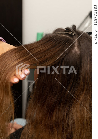 The hairdresser holds the strands of the client's hair in his hands. Barbershop 118771283