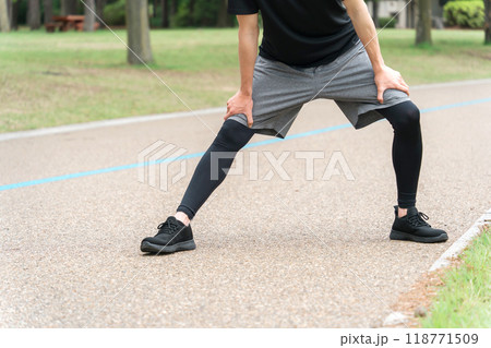 公園で運動前の準備運動・ウォーミングアップで膝屈伸するスポーツウェアの男性 公園で運動前の準備運動・ウォーミングアップで膝屈伸するスポーツウェアの男性 118771509
