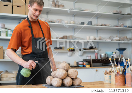 The potter wets the clay before using it in the workshop. 118771559