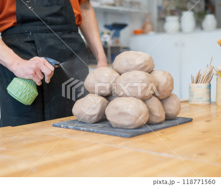 The potter wets the clay before using it in the workshop. The potter wets the clay before using it in the workshop. 118771560