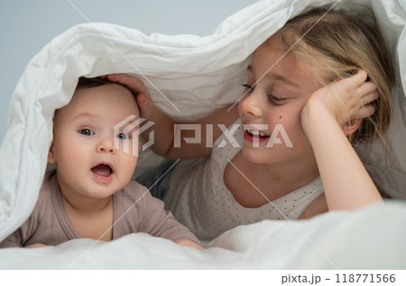 Little girl and her newborn brother hiding under the blanket.  118771566