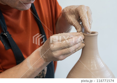 Close-up of a potter's hands making a ceramic vase on a potter's wheel. Close-up of a potter's hands making a ceramic vase on a potter's wheel. 118771574