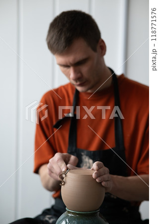 A potter works with a tool on a potter's wheel. A potter works with a tool on a potter's wheel. 118771576