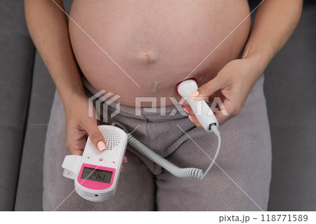 Close-up of a pregnant woman's belly using a home doppler. Normal baby heartbeat. Close-up of a pregnant woman's belly using a home doppler. Normal baby heartbeat. 118771589