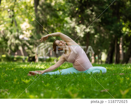 Pregnant caucasian woman doing yoga in the park. Lateral tilt. Pregnant caucasian woman doing yoga in the park. Lateral tilt. 118772025