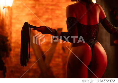 Woman in underwear holds a whip against the background of her buttocks. Woman in underwear holds a whip against the background of her buttocks. 118772472