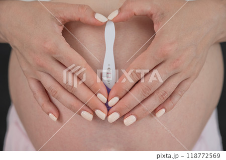 Caucasian woman holding a positive express pregnancy test against the background of her tummy. Caucasian woman holding a positive express pregnancy test against the background of her tummy. 118772569
