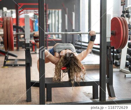 Middle aged woman doing bench press at the gym. Middle aged woman doing bench press at the gym. 118772629
